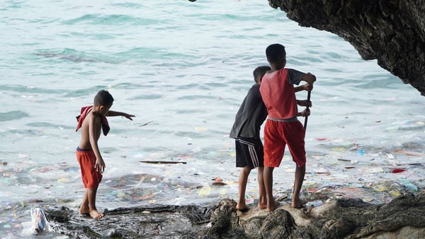 Image shows 3 young boys by the ocean 