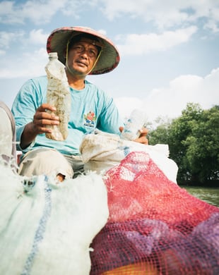 Image shows an Indonesian fisherman with waste collected from the ocean 